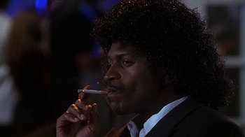 Movie still from “How to Be a Player” (1997), directed by Lionel C. Martin – A man in a black suit smoking a cigarette; Close Up shot, Low angle