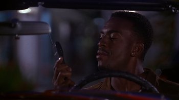 Movie still from “How to Be a Player” (1997), directed by Lionel C. Martin – A man in a car looking at his cell phone; Close Up shot, High angle