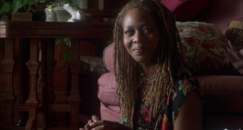 Movie still from “How to Make an American Quilt” (1995), directed by Jocelyn Moorhouse – A woman sitting in a chair with dreadlocks; Close Up shot, Over the shoulder angle