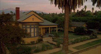 Movie still from “How to Make an American Quilt” (1995), directed by Jocelyn Moorhouse – A yellow house sitting next to a palm tree; Extreme Wide shot, High angle