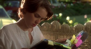 Movie still from “How to Make an American Quilt” (1995), directed by Jocelyn Moorhouse – A woman sitting on a porch swing reading a book; Close Up shot, Over the shoulder angle