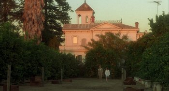 Movie still from “How to Make an American Quilt” (1995), directed by Jocelyn Moorhouse – Two people are walking in front of a large house; Extreme Wide shot, Low angle