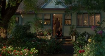 Movie still from “How to Make an American Quilt” (1995), directed by Jocelyn Moorhouse – A man and a woman sitting in front of a house; Wide shot, High angle