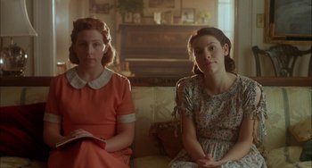 Movie still from “How to Make an American Quilt” (1995), directed by Jocelyn Moorhouse – Two young women sitting on a couch in a living room; Medium shot, Low angle