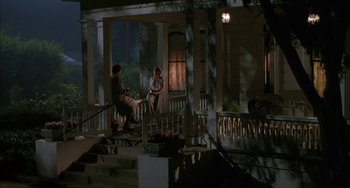 Movie still from “How to Make an American Quilt” (1995), directed by Jocelyn Moorhouse – Two people sitting on a porch at night; Wide shot, High angle