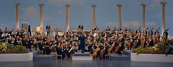 Movie still from “How to Marry a Millionaire” (1953), directed by Jean Negulesco – A group of people that are standing in a room; Extreme Wide shot, High angle