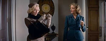 Movie still from “How to Marry a Millionaire” (1953), directed by Jean Negulesco – Two women standing next to each other in front of a wall clock; Medium shot, Low angle