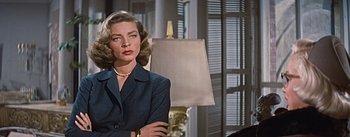 Movie still from “How to Marry a Millionaire” (1953), directed by Jean Negulesco – A woman standing in front of a lamp in front of a window; Close Up shot, Low angle