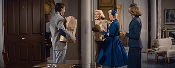 Movie still from “How to Marry a Millionaire” (1953), directed by Jean Negulesco – A man and two women holding paper bags; Medium shot, High angle