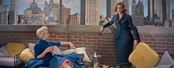 Movie still from “How to Marry a Millionaire” (1953), directed by Jean Negulesco – A woman in a blue suit stands in front of another woman in a blue suit; Medium shot, Low angle