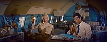 Movie still from “How to Marry a Millionaire” (1953), directed by Jean Negulesco – A man and a woman sitting at a table with drinks; Medium shot, Low angle