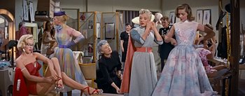 Movie still from “How to Marry a Millionaire” (1953), directed by Jean Negulesco – An older woman is putting on a red belt; Medium shot, Low angle