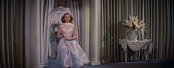 Movie still from “How to Marry a Millionaire” (1953), directed by Jean Negulesco – A woman in a dress holding an open umbrella; Medium shot, Low angle