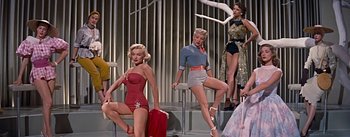 Movie still from “How to Marry a Millionaire” (1953), directed by Jean Negulesco – A group of women standing next to each other on a stage; Wide shot, Low angle