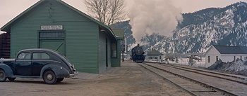 Movie still from “How to Marry a Millionaire” (1953), directed by Jean Negulesco – A train is coming down the tracks near a building; Extreme Wide shot, Low angle