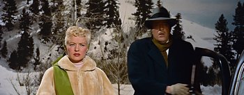 Movie still from “How to Marry a Millionaire” (1953), directed by Jean Negulesco – A man and a woman standing next to each other in front of trees; Medium shot, Low angle