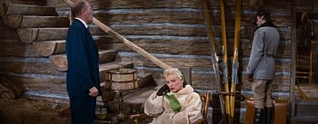 Movie still from “How to Marry a Millionaire” (1953), directed by Jean Negulesco – A woman sitting in a rocking chair holding a cell phone up to her ear; Wide shot, Low angle