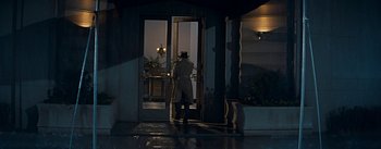 Movie still from “How to Marry a Millionaire” (1953), directed by Jean Negulesco – A man in a raincoat is standing at the entrance of a building; Wide shot, Low angle