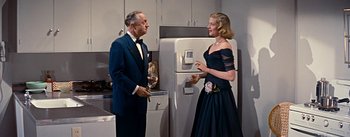 Movie still from “How to Marry a Millionaire” (1953), directed by Jean Negulesco – A man and a woman standing in front of a refrigerator; Medium shot, Low angle