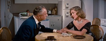 Movie still from “How to Marry a Millionaire” (1953), directed by Jean Negulesco – An older man and a younger woman sitting at a table; Medium shot, Over the shoulder angle