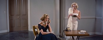 Movie still from “How to Marry a Millionaire” (1953), directed by Jean Negulesco – A woman sitting on a chair talking on the phone; Medium shot, Over the shoulder angle