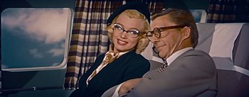 Movie still from “How to Marry a Millionaire” (1953), directed by Jean Negulesco – An older man sitting next to an older woman wearing glasses; Medium shot, Low angle