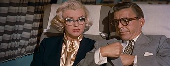 Movie still from “How to Marry a Millionaire” (1953), directed by Jean Negulesco – A woman wearing glasses sitting next to a man; Close Up shot, Low angle