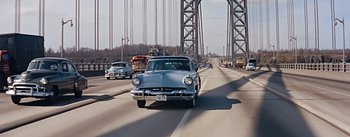 Movie still from “How to Marry a Millionaire” (1953), directed by Jean Negulesco – An old car is driving down the highway; Extreme Wide shot, High angle