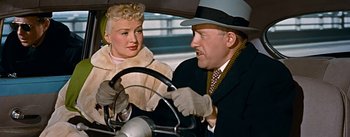 Movie still from “How to Marry a Millionaire” (1953), directed by Jean Negulesco – A man and a woman are sitting in the drivers seat of a car; Close Up shot, Over the shoulder angle