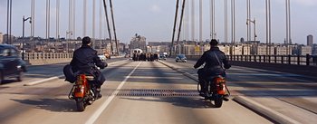 Movie still from “How to Marry a Millionaire” (1953), directed by Jean Negulesco – A group of people on motorcycles on a bridge; Wide shot, High angle