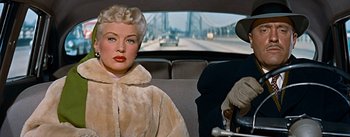 Movie still from “How to Marry a Millionaire” (1953), directed by Jean Negulesco – An older woman sitting in the back seat of a car; Close Up shot, Over the shoulder angle