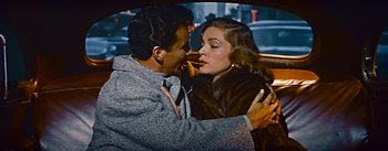 Movie still from “How to Marry a Millionaire” (1953), directed by Jean Negulesco – A man and a woman kissing in the back of a car; Medium shot, High angle