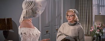 Movie still from “How to Marry a Millionaire” (1953), directed by Jean Negulesco – Two women are sitting in front of each other in a room; Medium shot, Over the shoulder angle