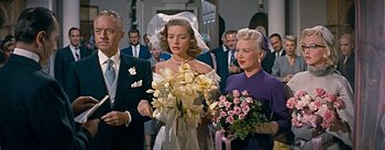 Movie still from “How to Marry a Millionaire” (1953), directed by Jean Negulesco – A bride and her mother walk down the aisle; Medium shot, Over the shoulder angle