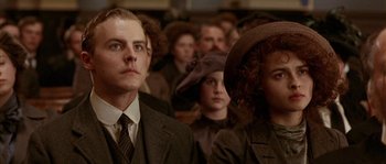 Movie still from “Howards End” (1992), directed by James Ivory – A group of people sitting in front of each other wearing suits; Close Up shot, Low angle
