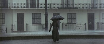 Movie still from “Howards End” (1992), directed by James Ivory – A woman walking down the street holding an umbrella; Wide shot, Low angle