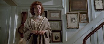 Movie still from “Howards End” (1992), directed by James Ivory – A woman standing in front of a bunch of framed pictures; Medium shot, Low angle