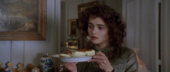 Movie still from “Howards End” (1992), directed by James Ivory – A woman holding a plate of food while looking at the camera; Close Up shot, Over the shoulder angle
