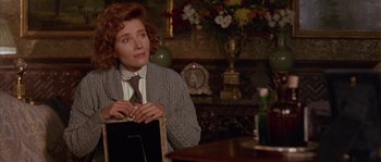 Movie still from “Howards End” (1992), directed by James Ivory – A woman sitting at a table with a bag; Medium shot, Over the shoulder angle