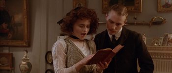 Movie still from “Howards End” (1992), directed by James Ivory – A woman reading a book while standing next to a man; Close Up shot, Low angle