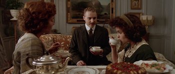 Movie still from “Howards End” (1992), directed by James Ivory – Three people sitting at a table drinking tea; Medium shot, High angle