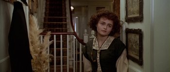 Movie still from “Howards End” (1992), directed by James Ivory – A woman standing in a room next to a staircase; Close Up shot, High angle