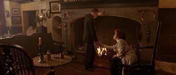 Movie still from “Howards End” (1992), directed by James Ivory – A man and a woman standing in front of a fireplace; Wide shot, High angle