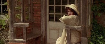Movie still from “Howards End” (1992), directed by James Ivory – A woman sitting in front of a brick building; Medium shot, High angle