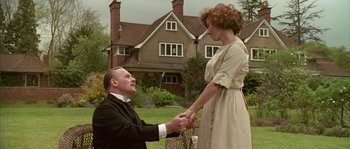 Movie still from “Howards End” (1992), directed by James Ivory – A man and a woman holding hands in front of a house; Medium shot, Low angle