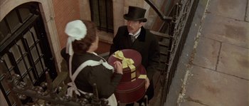Movie still from “Howards End” (1992), directed by James Ivory – A man in a top hat holding a hat box; Medium shot, High angle