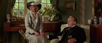 Movie still from “Howards End” (1992), directed by James Ivory – An older man and a younger woman holding hands in a living room; Medium shot, Low angle