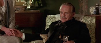 Movie still from “Howards End” (1992), directed by James Ivory – An older man sitting in a chair holding a glass; Close Up shot, Low angle