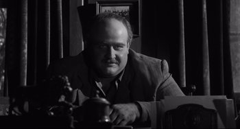 Movie still from “Hush...Hush, Sweet Charlotte” (1964), directed by Robert Aldrich – Black and white photograph of a man leaning on a table; Close Up shot, Low angle