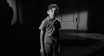 Movie still from “Hush...Hush, Sweet Charlotte” (1964), directed by Robert Aldrich – A young boy standing in front of an open door; Medium shot, High angle